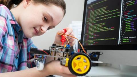 Computing and engineering student using programming software with robot